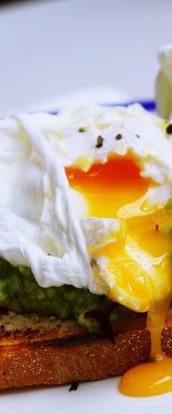 Poached egg with avocado on white plate